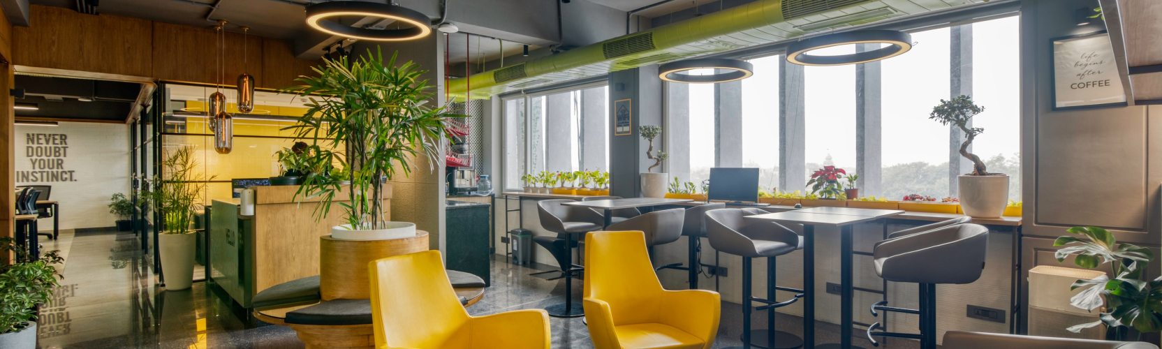 Modern coworking lounge with yellow meeting table and glass-partition offices