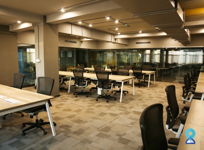 Modern open coworking office with rows of desks and ergonomic chairs